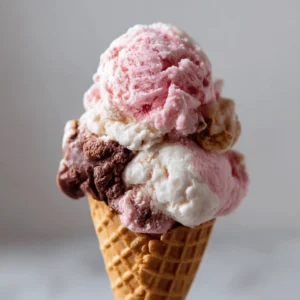 Triple-scoop Neapolitan ice cream cone with strawberry, vanilla, and chocolate flavors.